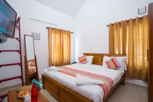 Cozy bedroom at Misty Lake Resort Munnar featuring modern interiors, comfortable bedding, and a private balcony with scenic hill views.