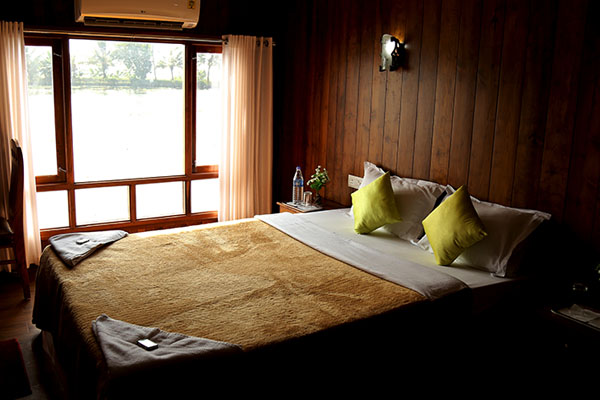 Fully furnished air-conditioned bedroom inside a luxury Kerala houseboat in Alleppey backwaters