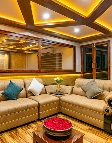 Luxury houseboat in Alappuzha lobby with cream sofas, wooden ceiling and warm lighting